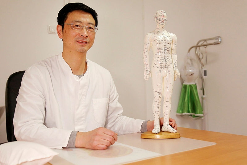 Herr Chunhua Cen am Tisch sitzend. Im Artikel: Kleine Nadeln gegen chronische Schmerzen