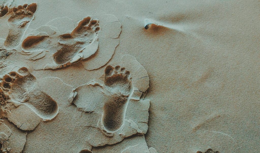 Fußspuren im Sand. Im Artikel: Warum barfuß laufen gesund ist