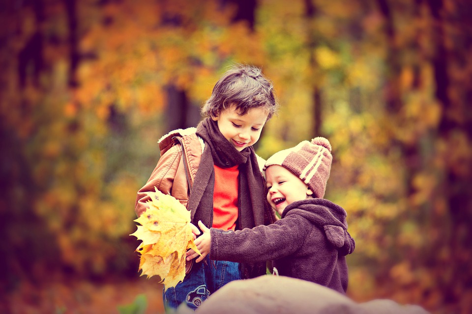 Zwei Kinder spielen im Wald mit Blättern. Im Artikel: Mit der Natur die Zähne putzen