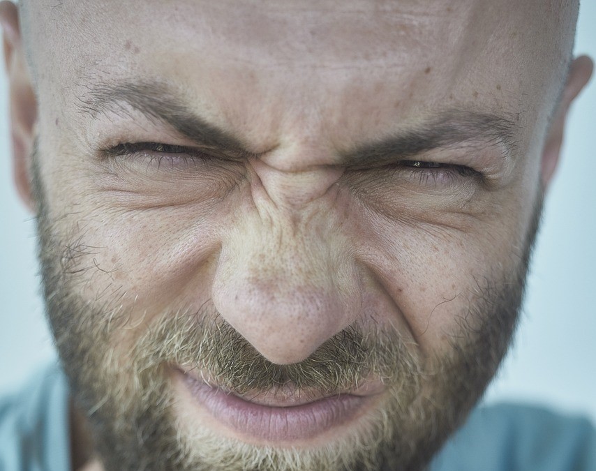 Ein Mann mit Bart zieht Augen und Mund zusammen, er hat sichtbar Probleme mit der Nase